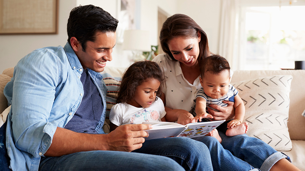 Family of 4 reading together on couch